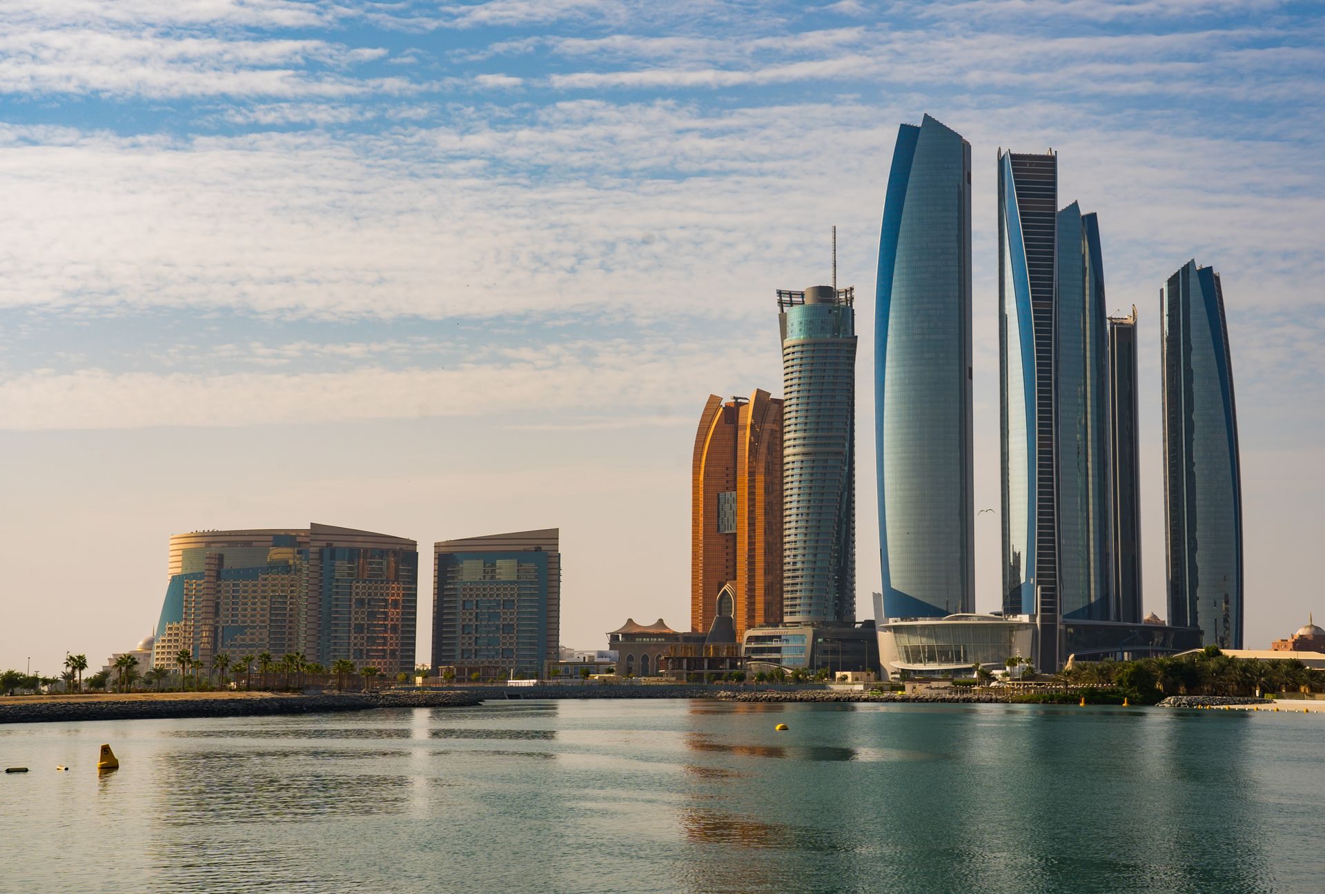 Abu Dhabi skyline at dusk with modern towers reflected in the water